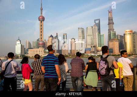 People stand on the waterfront overlooking the Huangpu River and skyscrapers in the Pudong business district of Shanghai, China Stock Photo