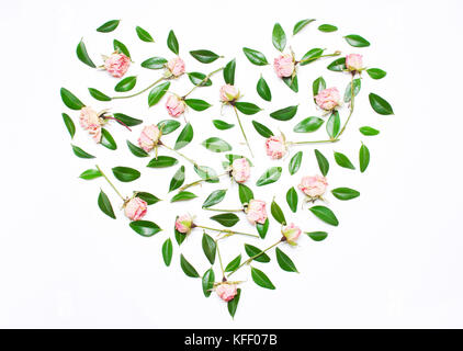 Pink flowers, green leaves in the shape of a heart on a white background. The concept of a holiday of love. Top view, flat Stock Photo