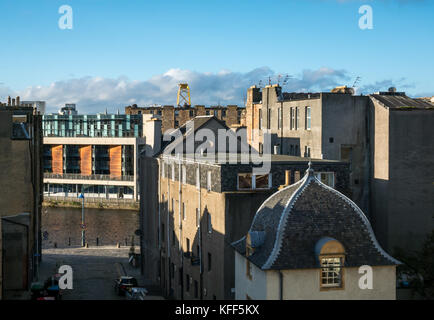 View over rooftops of old and modern buildings in Leith, Edinburgh, Scotland, UK, with huge yellow wind turbine platform in the distance Stock Photo