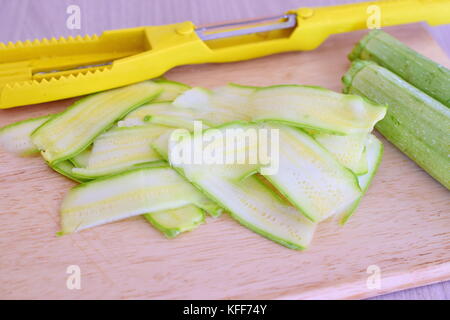 Fresh zucchini sliced with a slicer on a wooden cutting board. Step by step cooking Stock Photo