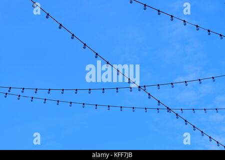 Row of Electric Light Bulbs Hanging on The Wire Against Beautiful Blue Sky. Stock Photo