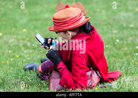 The senior woman dressed in red, uses her mobile phone, rear view Stock Photo