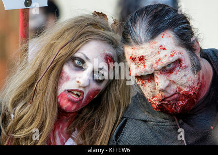 Bristol, UK. 28th Oct, 2017. A man and a woman dressed as zombies are pictured as they participate in a zombie walk through the city centre. Stock Photo
