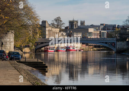 Autumn sun & beautiful York waterside setting (calm water of River Ouse, Lendal Bridge, boat moorings, historic buildings) - Yorkshire, England, UK. Stock Photo