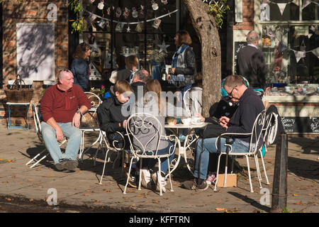 Tables & chairs outside street cafe, people on holiday enjoying autumn sun, sitting, relaxing, having refreshments - College Street, York, England, UK Stock Photo