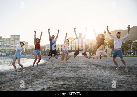 Portrait of group of happy friends jumping on beach Stock Photo