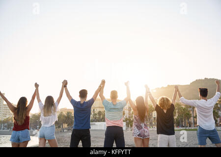 Back portrait of friends holding hands up together in victory gesture Stock Photo