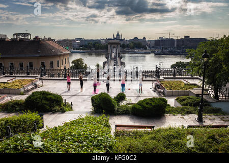 City of Budapest in Hungary, group of people practicing yoga on Castle Hill terrace garden facing Danube River Stock Photo