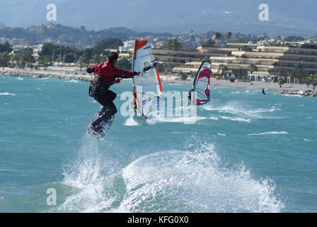 Kiteboarder taking off for a jump in front of windsurfer. St Laurent du Var, French Riviera Stock Photo