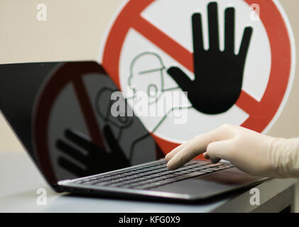 Male hand with glove at Notebook. Concept of stopping tinternet crime. Stock Photo