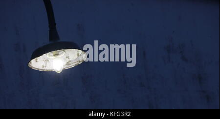 Vintage light fixture against weathered blue wall. Stock Photo