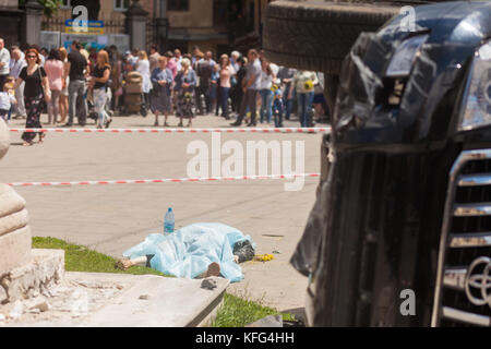 LVIV, UKRAINE - JUNE 18: The body of a pedestrian lays next to an overturned SUV on 18 June 2017 in Lviv, Ukraine. The accident occurred in front of a Stock Photo