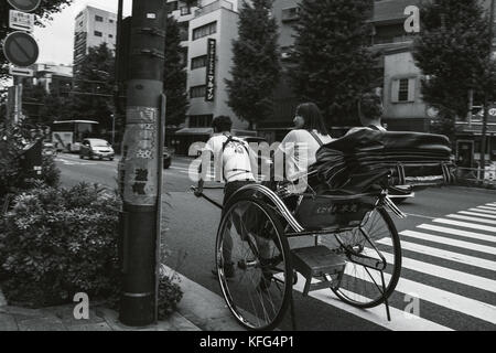 Moving shot of a rickshaw runner transporting customers in Asakusa, Tokyo. Stock Photo
