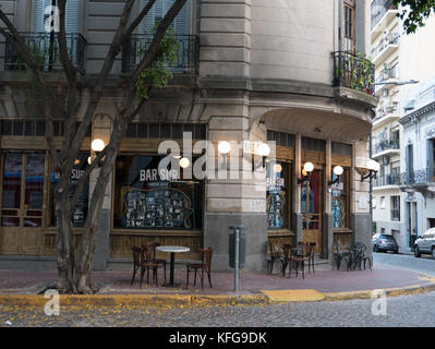 Empty tables in front of old, traditional local San Telmo bar, in Buenos Aires.  Globe lights on old wooden doors and empty street. Stock Photo