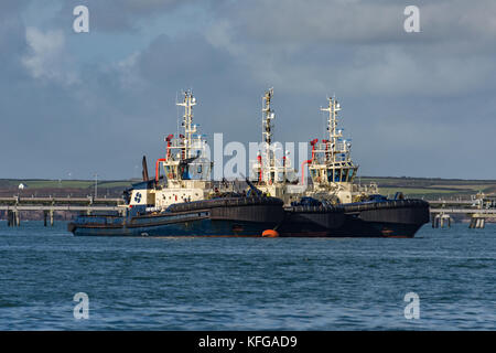 Three tugs at a mooring buoy by South Hook LNG terminal awaiting their next task. Stock Photo