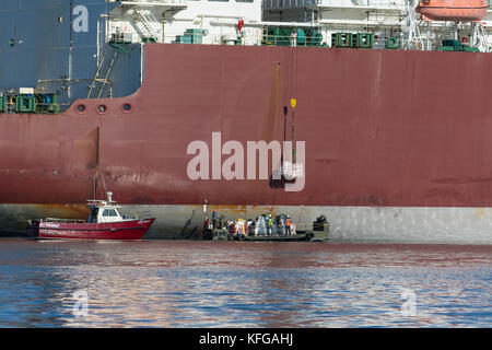 LNG supertanker loads from provisions stores barge Stock Photo