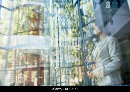Daydreaming Businesswoman Enjoying View behind Window Stock Photo