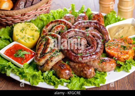 Assorted Bavarian sausages garnished with greens and sauces Stock Photo