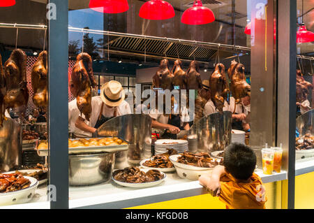 Roasted ducks hanging in window as boy watches at a restaurant in Shenzhen, Guangdong Province, China Stock Photo