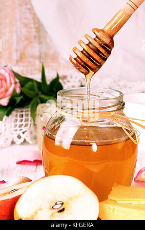 Breakfast with delicious sweet honey, cheese and pear. Glass gar of honey, piece of cheese, cup of tea, two half of pear, rose arranged over on white  Stock Photo