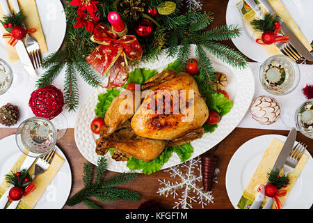 Baked turkey or chicken. The Christmas table is served with a turkey, decorated with bright tinsel and candles. Fried chicken, table. Christmas dinner Stock Photo