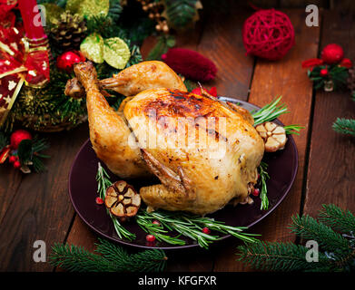 Baked turkey or chicken. The Christmas table is served with a turkey, decorated with bright tinsel and candles. Fried chicken, table. Christmas dinner Stock Photo