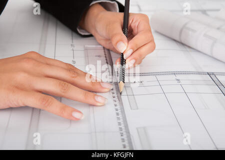 Cropped image of businesswoman working on blueprint at office Stock Photo