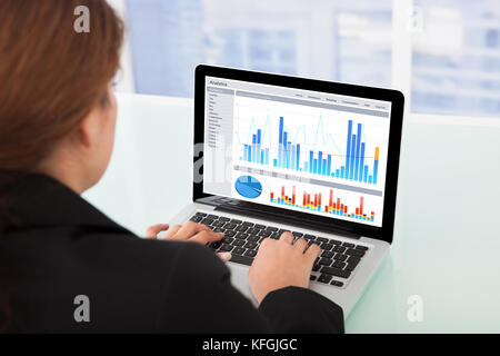 Cropped image of businesswoman watching financial charts on laptop in office Stock Photo