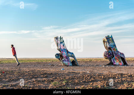 Amarillo, Texas, USA. 18th October 2015. One man playing by the side, in line with buried cars. Looking away and inclined, tilted sideways. Stock Photo