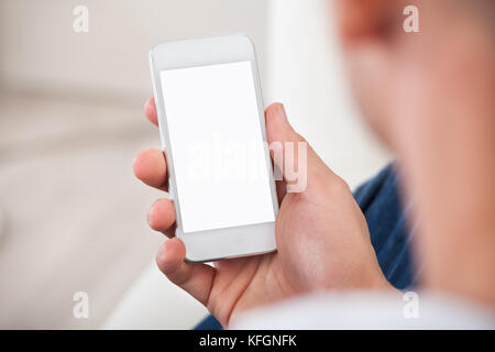 Over the shoulder view of the blank screen on a smartphone or mobile phone held in a mans hand Stock Photo