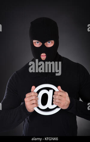 Hacker with computer wearing balaclava Stock Photo - Alamy