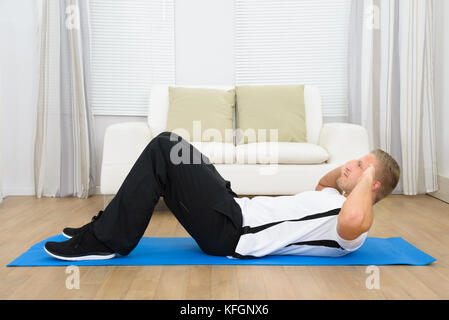 Sporty Young Man Doing Sits-up On Exercise Mat At Home Stock Photo