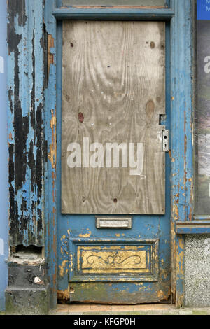 Boarded-up and peeling wooden door on disused and abandoned shop, Blaenau Ffestiniog, Wales. Stock Photo