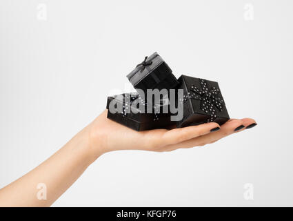 Female hand holding a three black gift-boxes on a palm. Isolated on white background. Shallow depth photo. Stock Photo