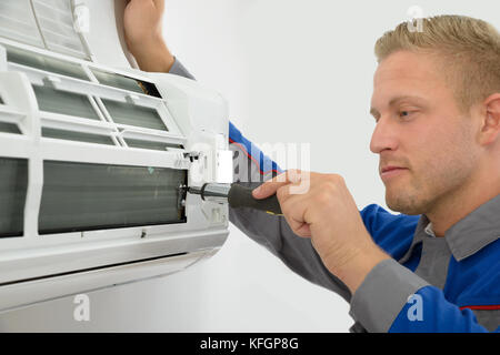 Portrait Of Young Male Technician Repairing Air Conditioner Stock Photo