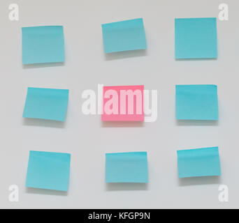 Single pink post it note in sea of blue post it notes Stock Photo