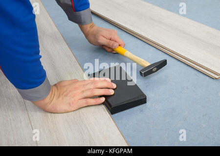 Close-up Of A Worker Assembling Laminate Floor Using A Hammer Stock Photo