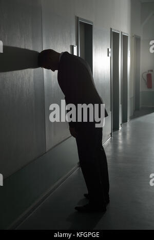 Portrait Of Disappointed Businessman Leaning On Wall In Office Stock Photo