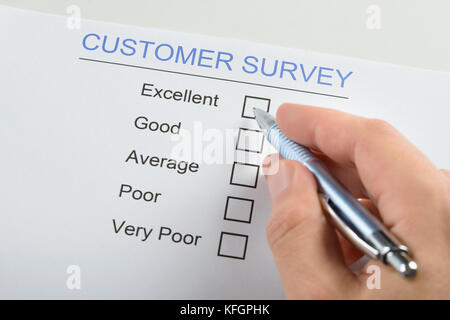 Close-up Of Person Hand Filling Customer Survey Form With Pen Stock Photo