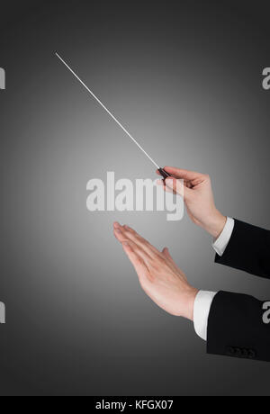 Cropped image of music conductor's hands holding baton against gray background Stock Photo