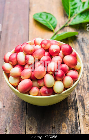 Fresh Thai Karanda in a bowl on wooden background with Copy space, Bengal-Currants, Carandas-plum Stock Photo