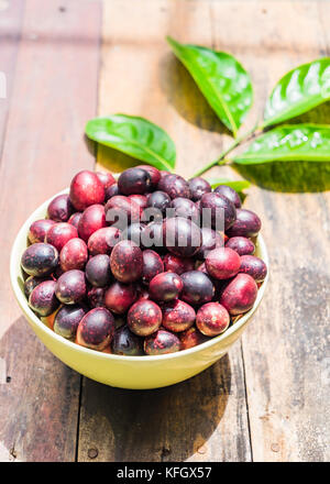 Fresh Thai Karanda in a bowl on wooden background with Copy space, Bengal-Currants, Carandas-plum Stock Photo