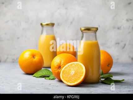 orange juice in glass bottles, fresh oranges on a gray concrete background Stock Photo