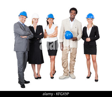Full length portrait of multiethnic architects with hardhats standing against white background Stock Photo