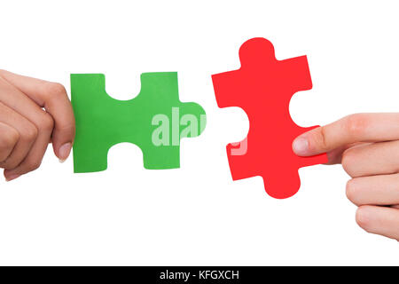 Cropped image of hands joining jigsaw puzzle pieces against white background Stock Photo