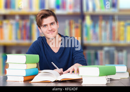 Portrait of smiling male college student studying at table in library Stock Photo
