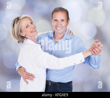 Portrait of affectionate couple dancing against colored background Stock Photo