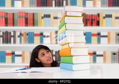 Shocked Woman In Library Looking At Stack Of Books Stock Photo
