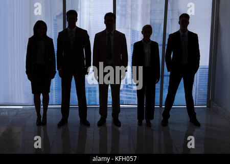 Silhouette team of business people standing together in office Stock Photo