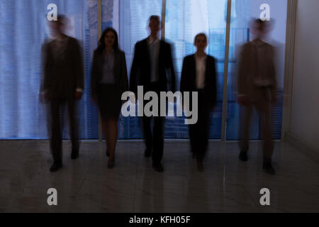 Blurred motion of business people walking in office corridor Stock Photo